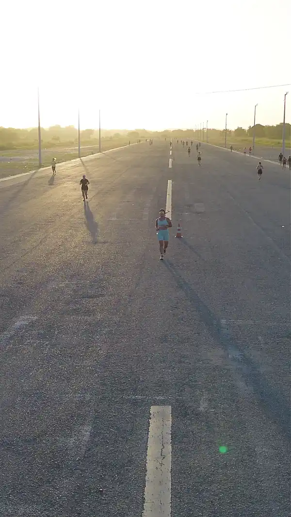 Vista aérea de Giorggia correndo em direção à câmera numa avenida de Sobral ao nascer do sol