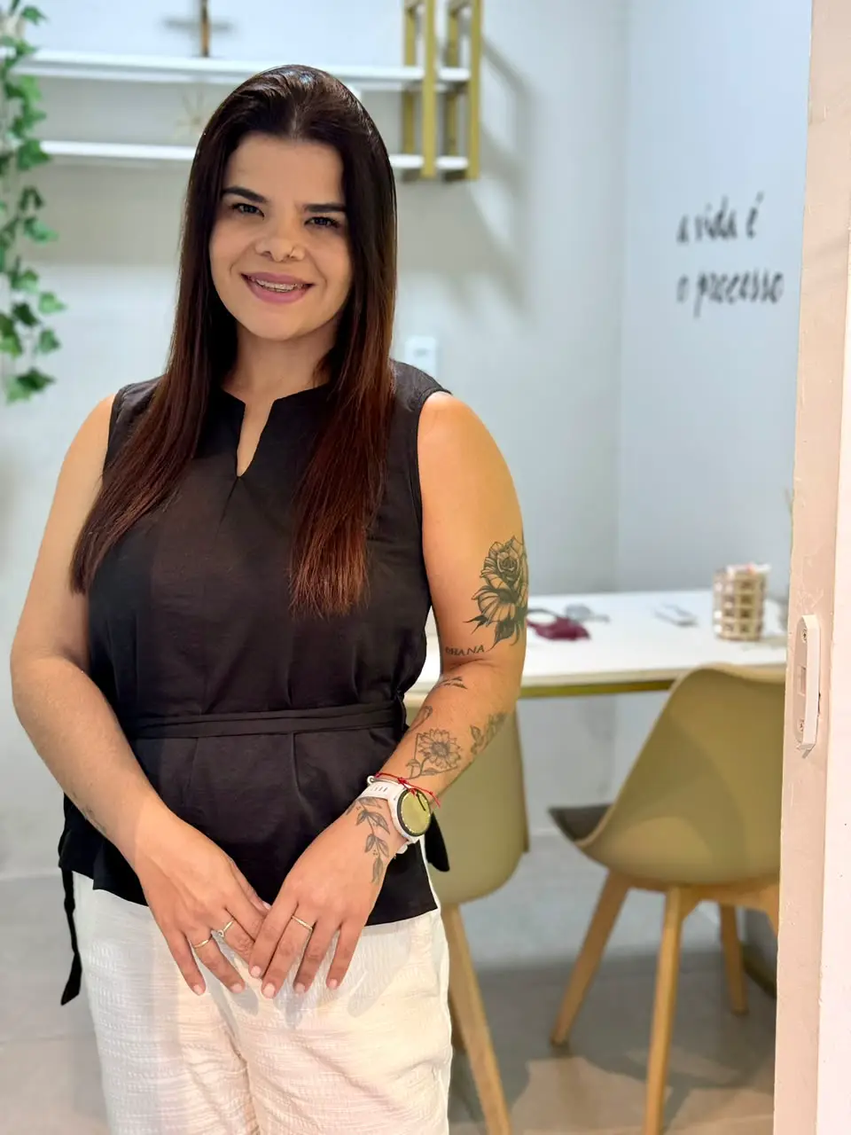 Giorggia sorrindo na porta do consultório, com a frase a vida é o processo escrita na parede