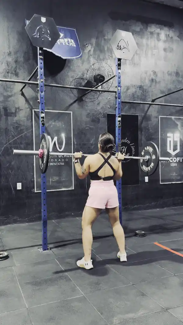 Giorggia no box de crossfit, de costas, levando a barra acima da cabeça